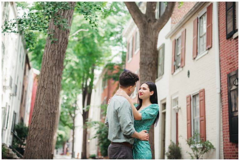 The couple embraces on a tree-lined street