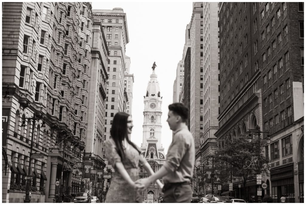 A black and white photo of the couple in front of Philadelphia City Hall in engagement photos in Philadelphia