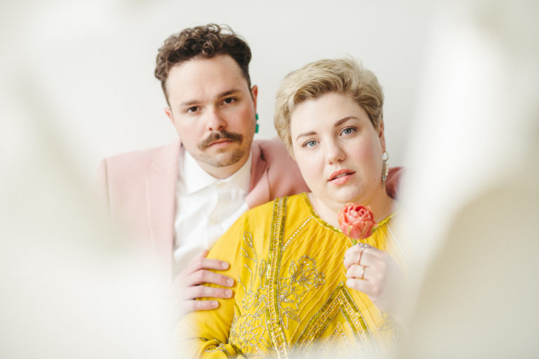 Steve and Devon, who’s holding a rose in her hand, looking into the camera during their artistic couple shoot with Jason Moody Photography