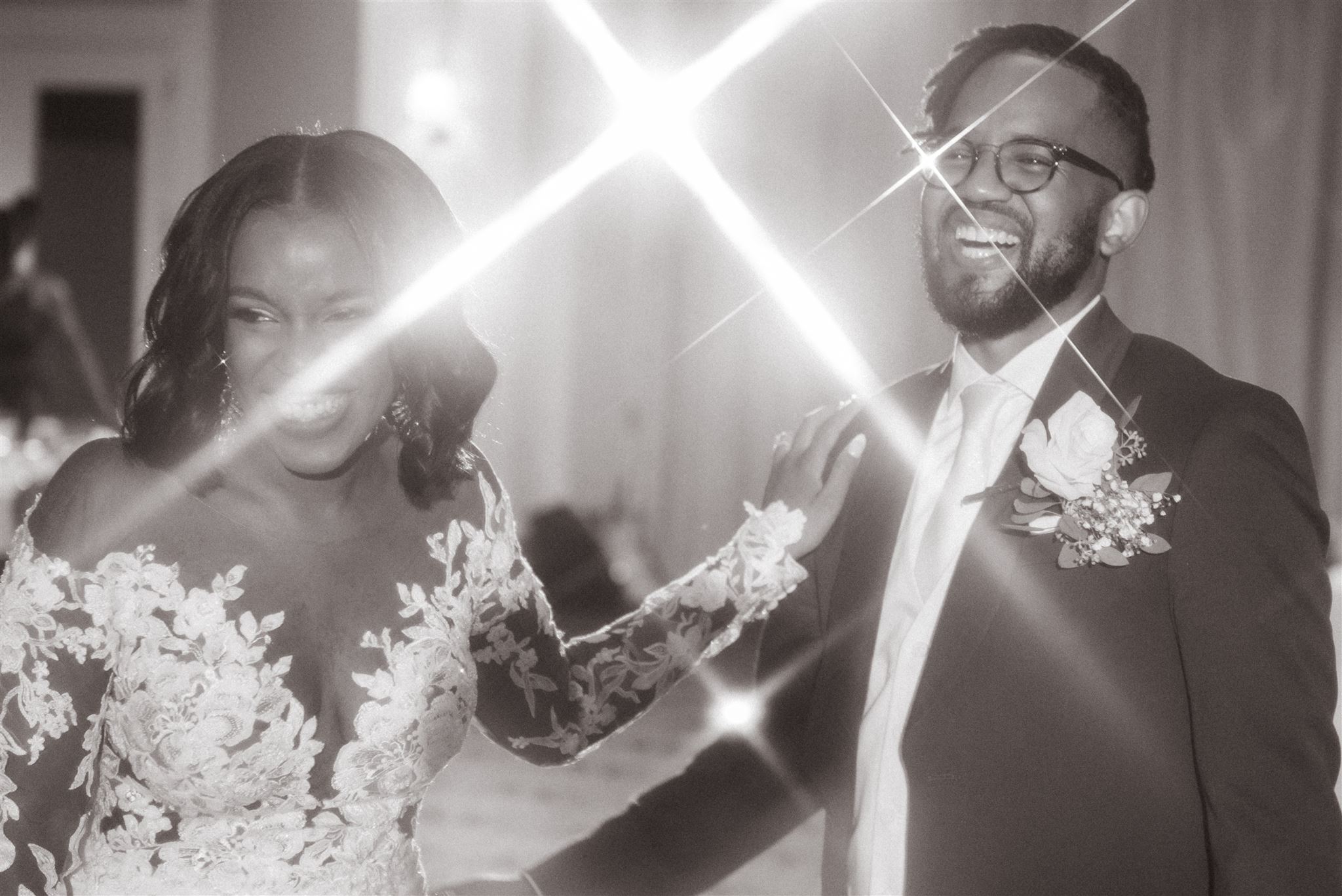 Why is Wedding Photography so Expensive + Why You Should Invest. Black and white photo of couple on dance floor with lights shining through.