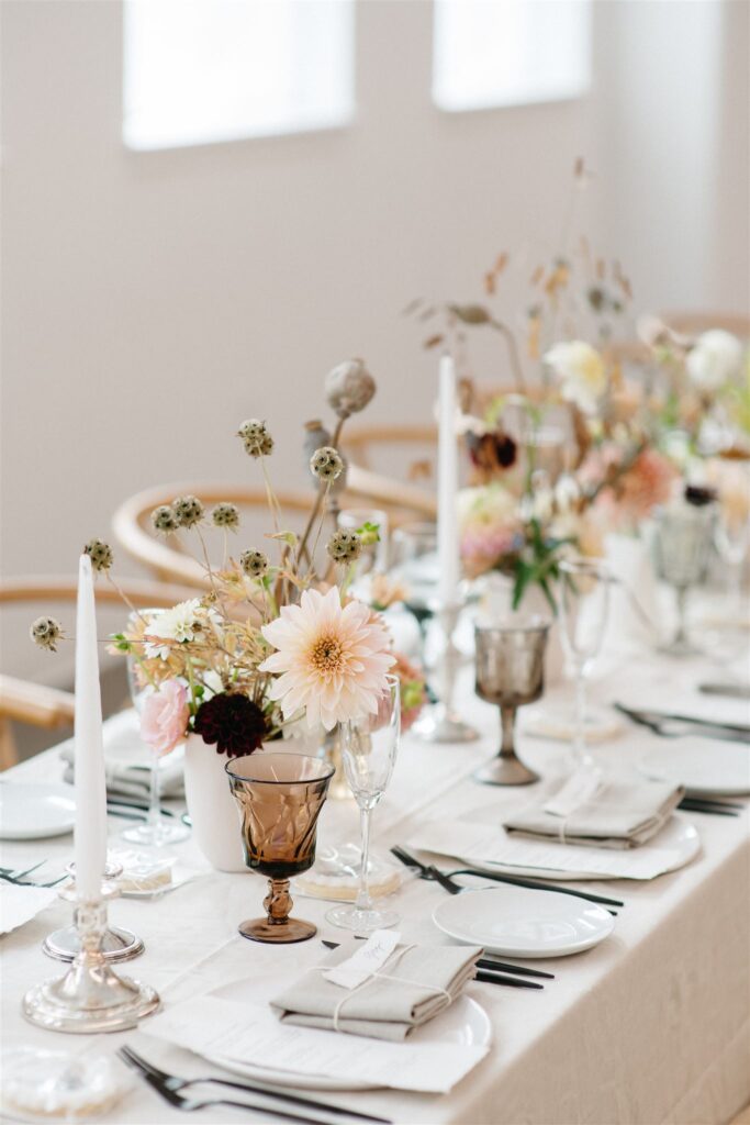 Shot for Kelly Giarrocco - Close-up shot of wedding reception table set up with a white, minimalist theme and floral centerpieces, photographed by Jason Moody Photography
