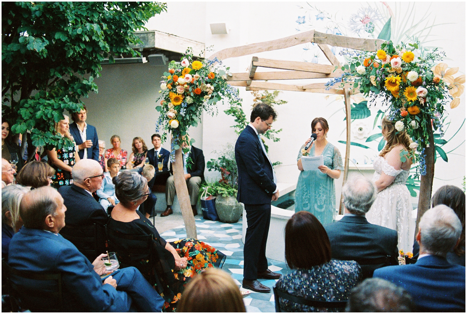 A couple gets married in the Suraya courtyard in front of a mural.