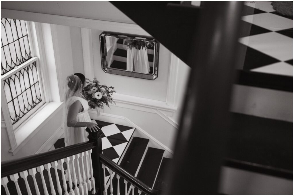 A bride walks down the black and white checkered staircase at Vaux Studio.