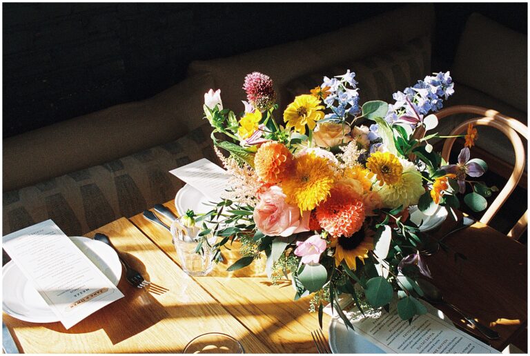 A colorful wedding bouquet sits on a wood table.