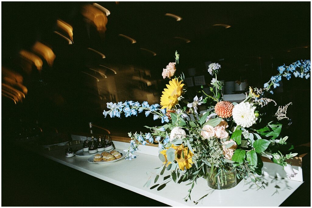 A bouquet sits on a reception table in a dark wedding venue.