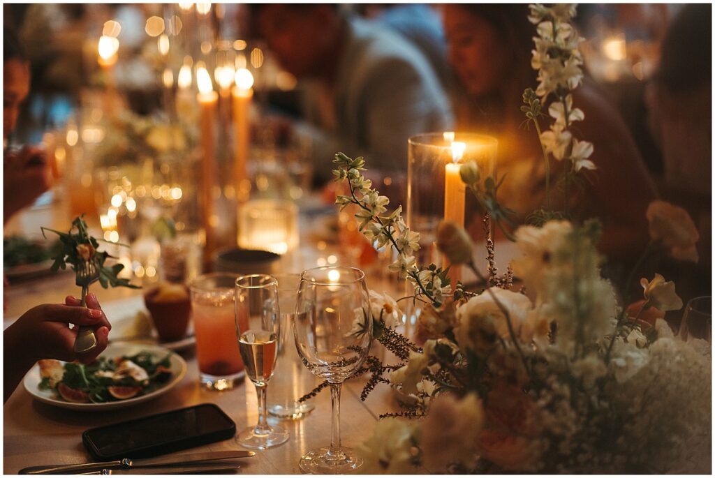 Guests eat salad at a candlelit wedding reception.