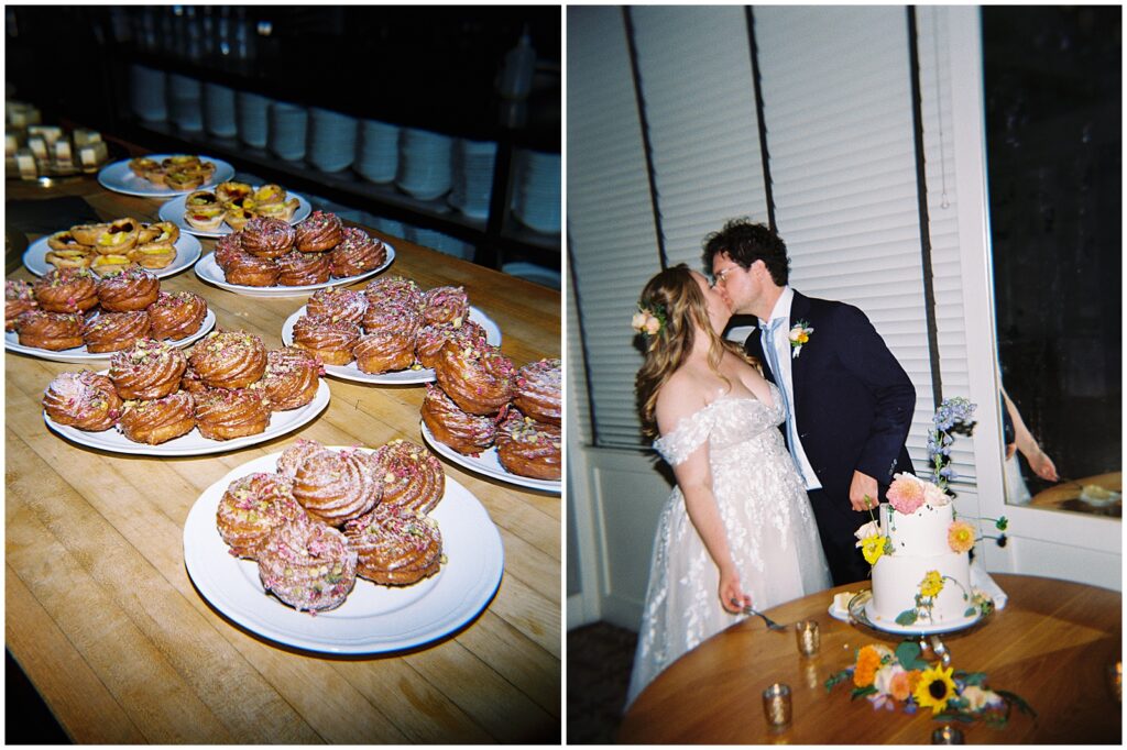 A bride and groom kiss beside a wedding cake decorated with flowers.
