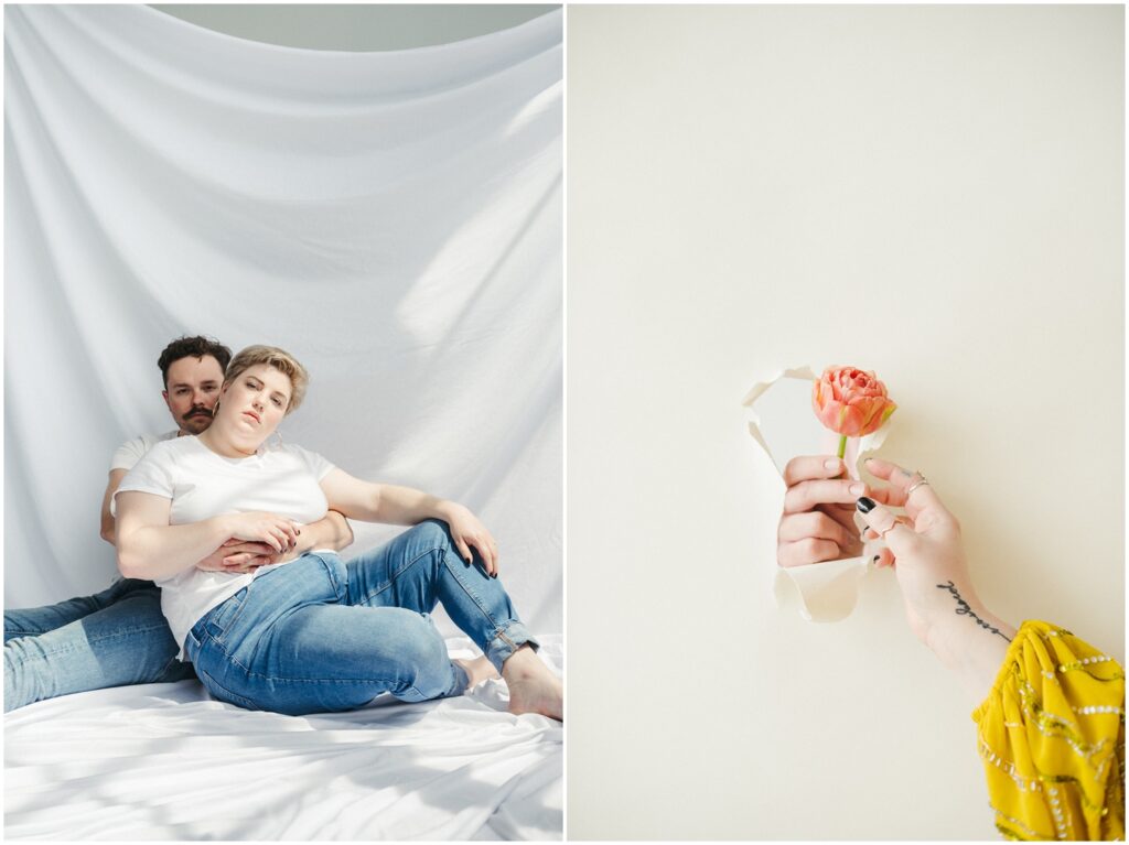 A couple cuddles in a studio in front of a white backdrop.