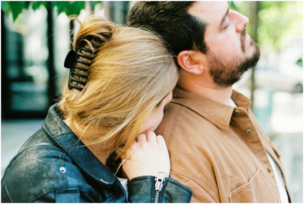 A woman leans her cheek against her partner's shoulder.