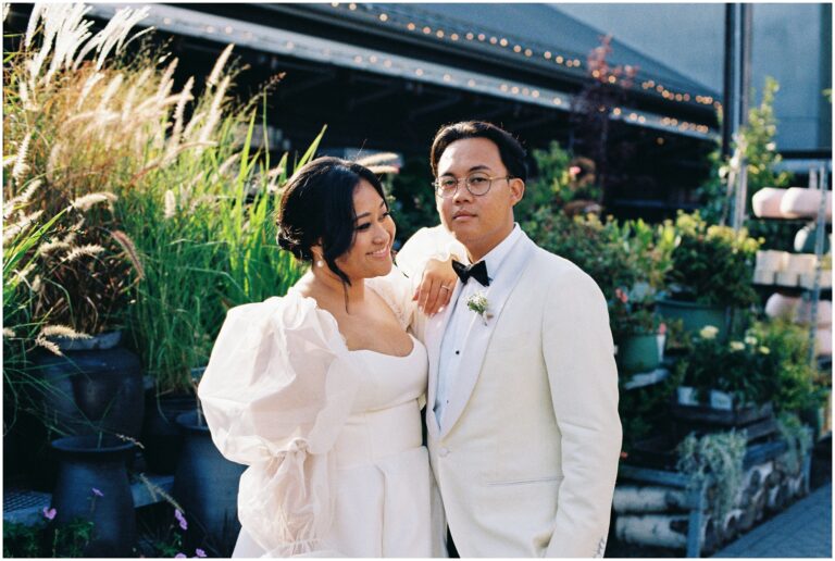 A bride leans her elbow on a groom's shoulder while posing for wedding photography.