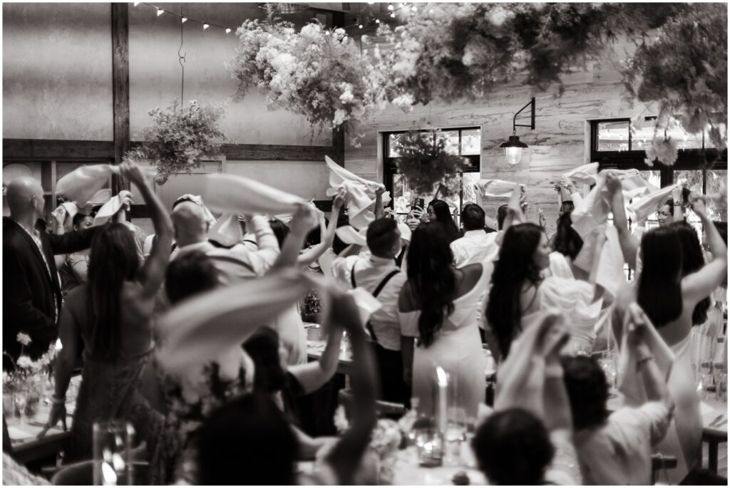 Guests wave napkins as a bride and groom enter their reception.
