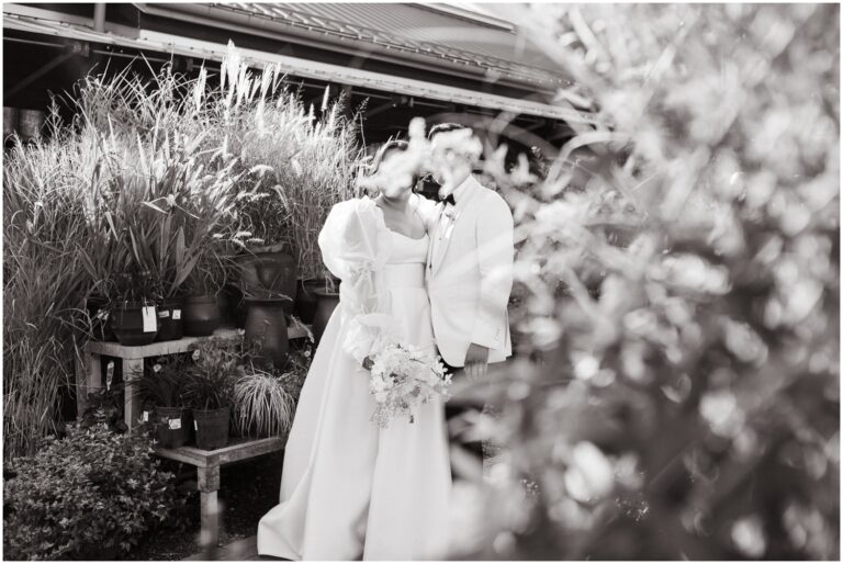 Behind a shrub, a bride and groom enter their Terrain wedding cocktail hour.