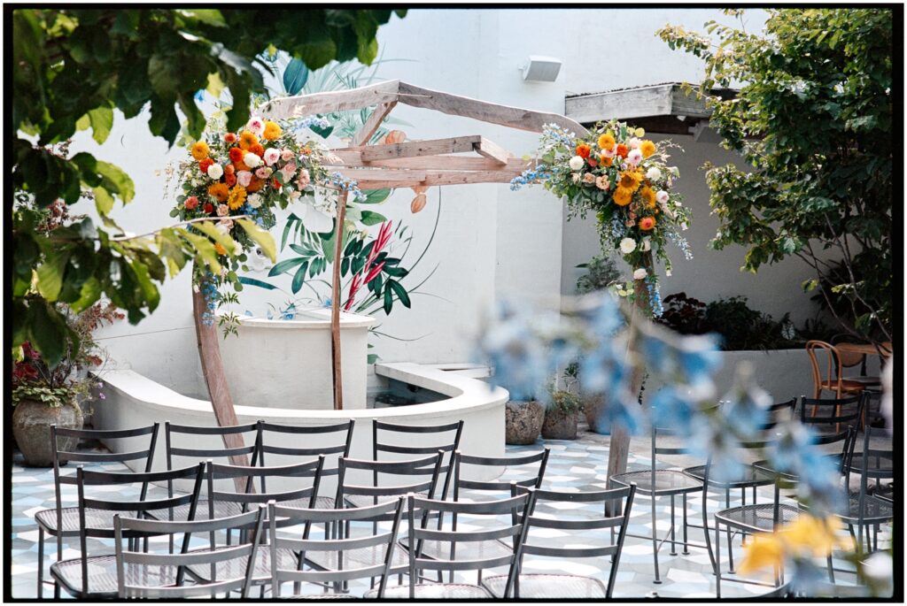 A floral wedding arbor and chairs sit in the courtyard of Suraya.