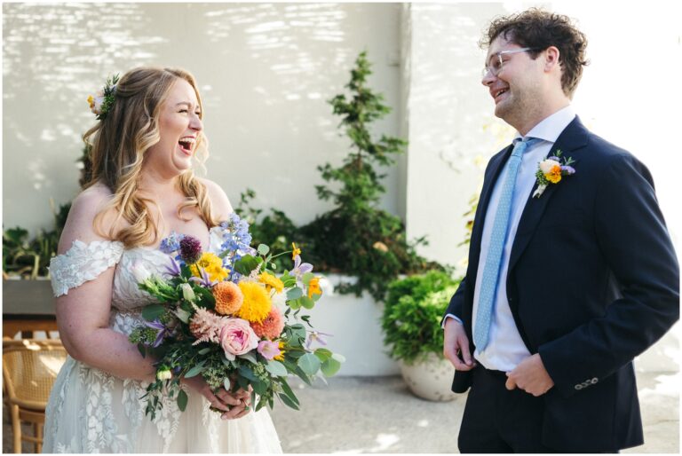 A bride and groom laugh during their first look at their Suraya wedding.