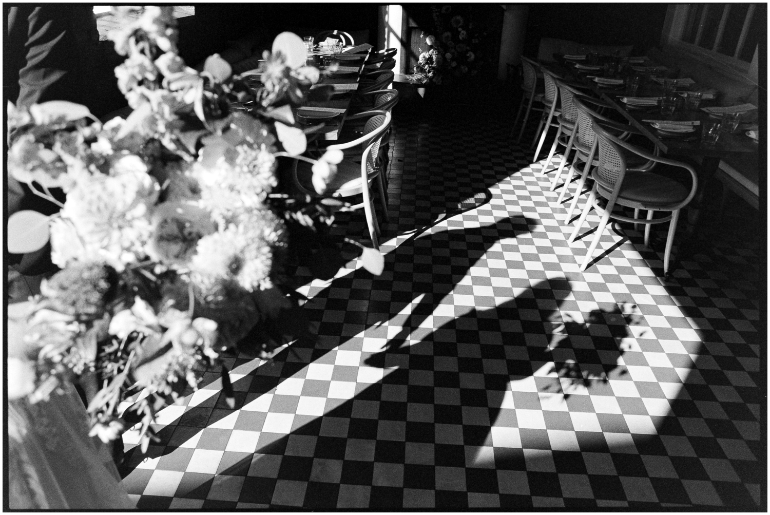 A bride and groom stand in the doorway of a Philadelphia wedding venue casting shadows on the tile floor.