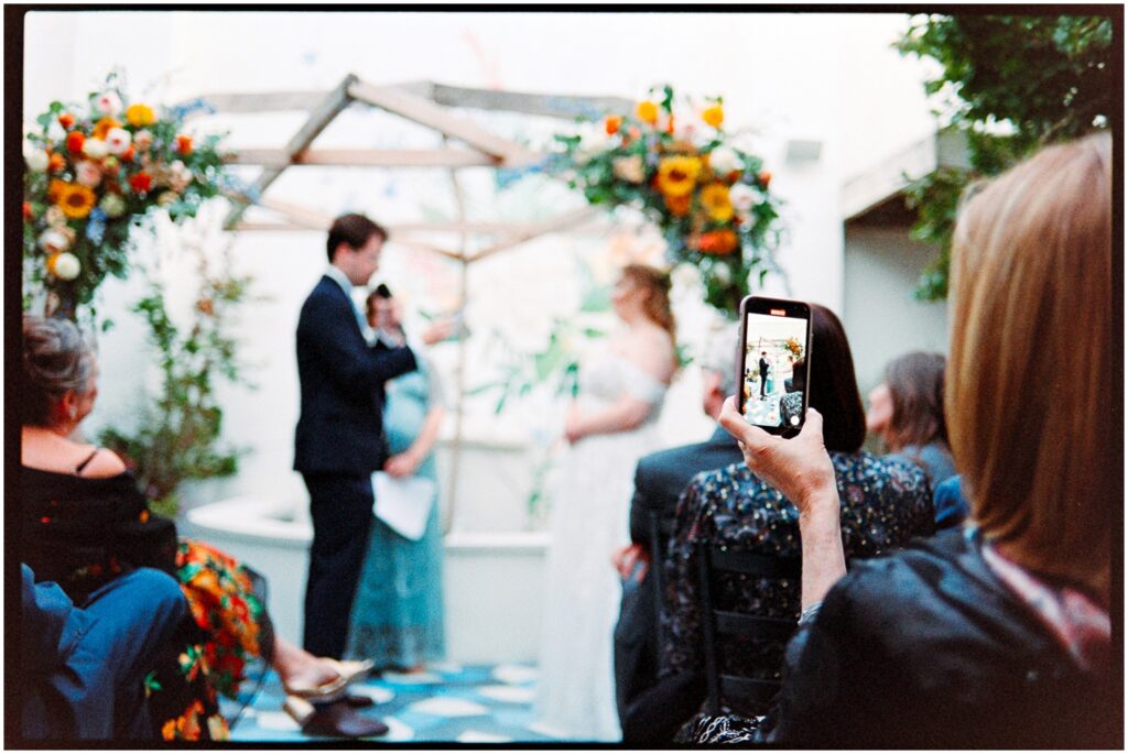 A guest records the wedding ceremony on her cell phone.