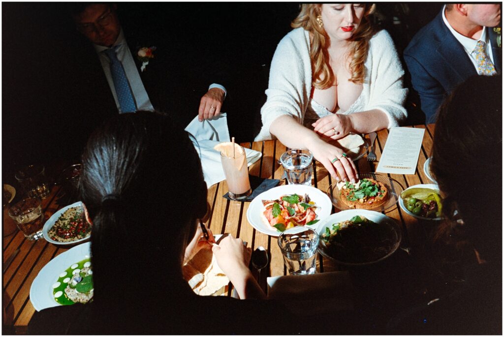 A bride reaches for a plate of dip in the middle of a reception table.