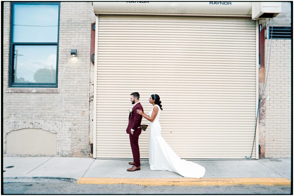 A bride taps a groom's shoulder for their first look on film wedding photography.