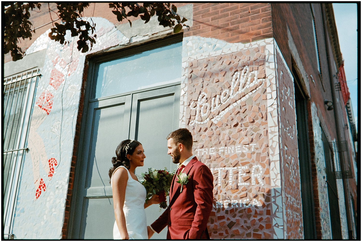 A bride and groom leans against a brick wall outside a Philadelphia restaurant.