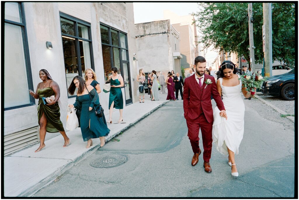 A bride and groom walk down a Philadelphia street to take wedding party portraits.