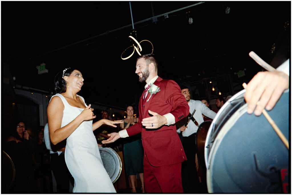 A groom holds his hands out to a bride on the dance floor.