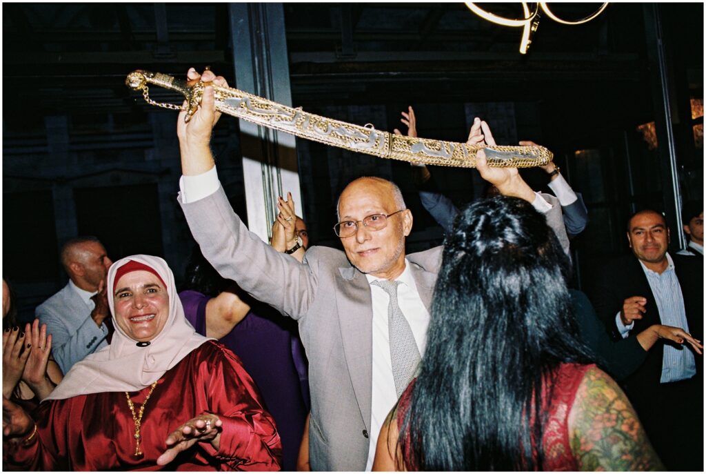 An older family member holds up a sword for a dance.