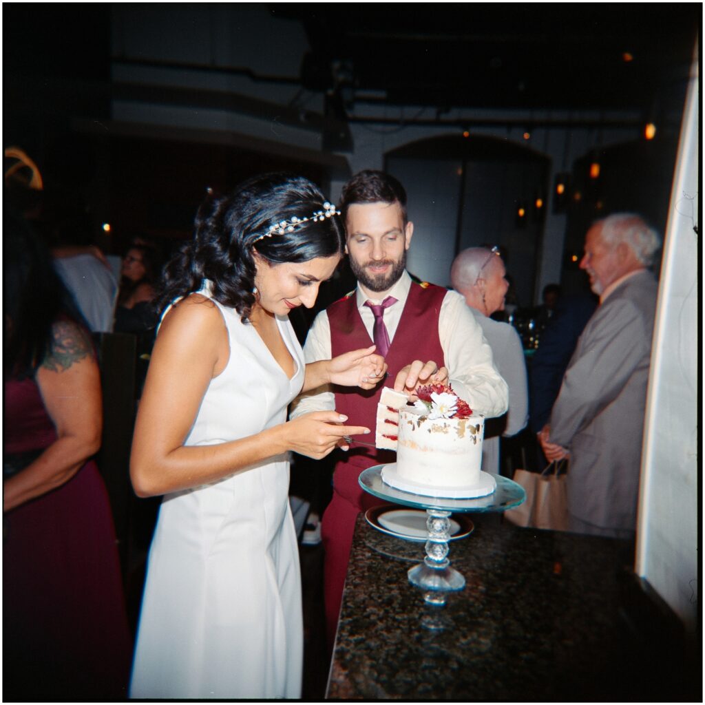 A bride and groom lift a piece of wedding cake.