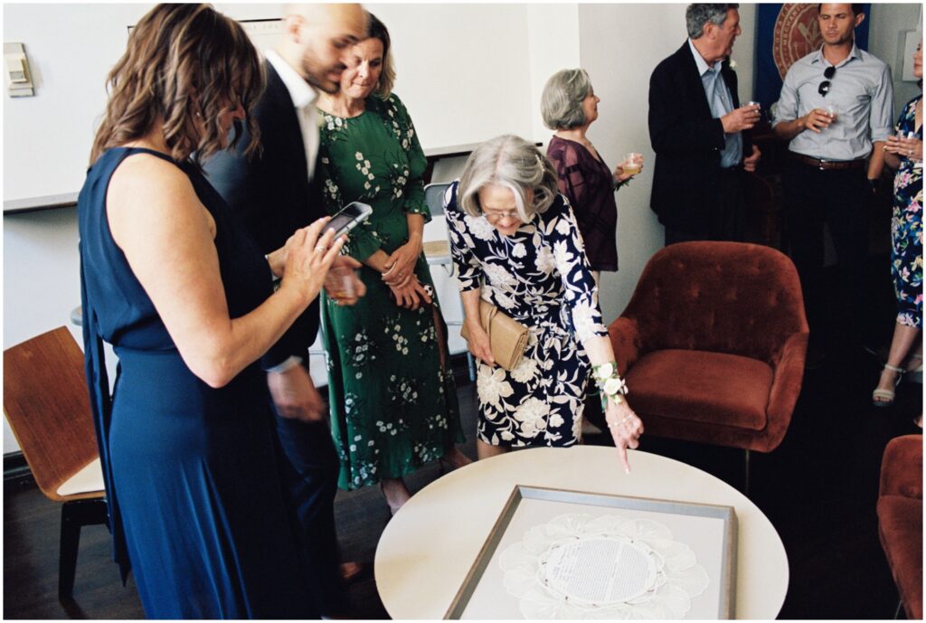 A family member points at a ketubah sitting on a table at a small wedding