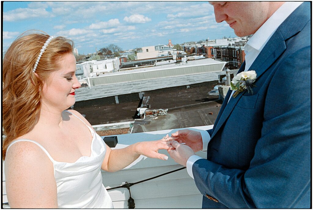 A groom puts a ring on a bride's finger at a Philadelphia wedding.