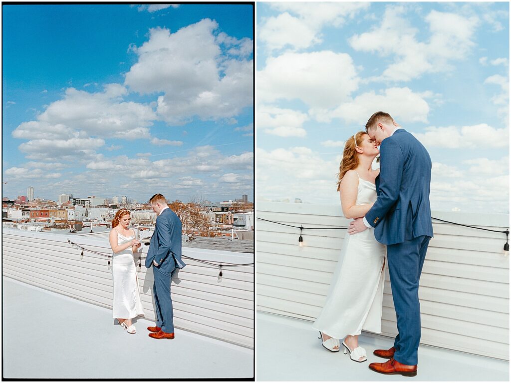 A couple in wedding attire reads their vows on a Philadelphia rooftop on a sunny day.