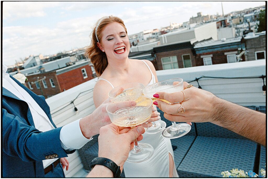 A bride, groom, and two witnesses clink champagne glasses on a Philadelphia rooftop.