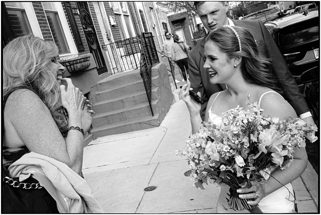 Two women greet a bride and groom on a Philadelphia sidewalk.