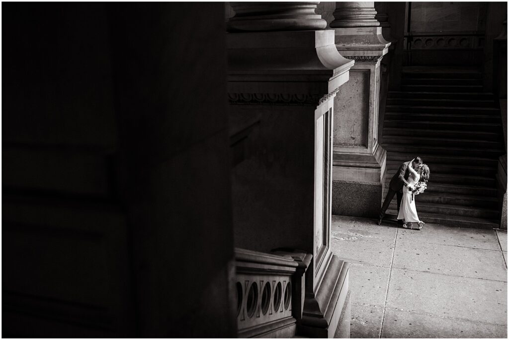 A bride and groom kiss at the foot of the stairs at their Philadelphia City Hall wedding.