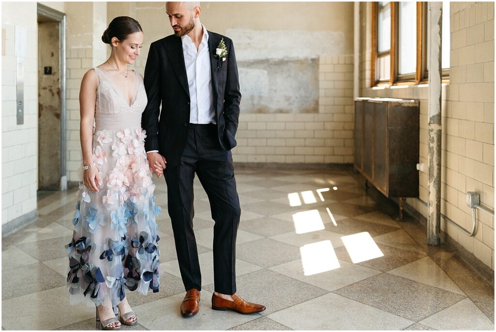 A bride and groom hold hands in a hallway of the BOK Building.