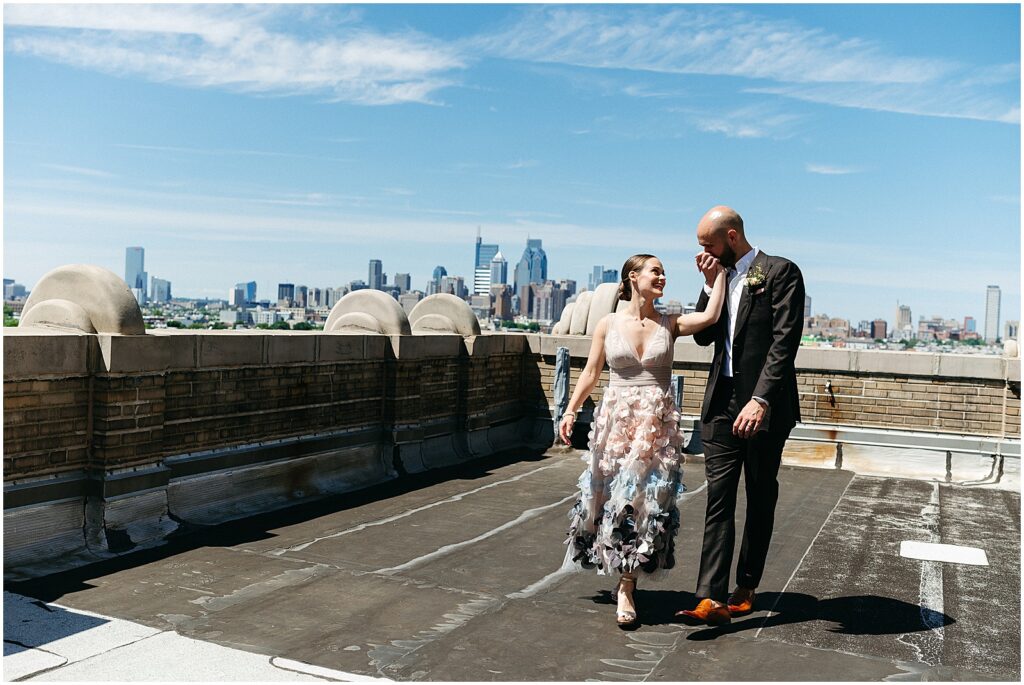 A bride and groom walk across a rooftop holding hands at their BOK Building wedding.