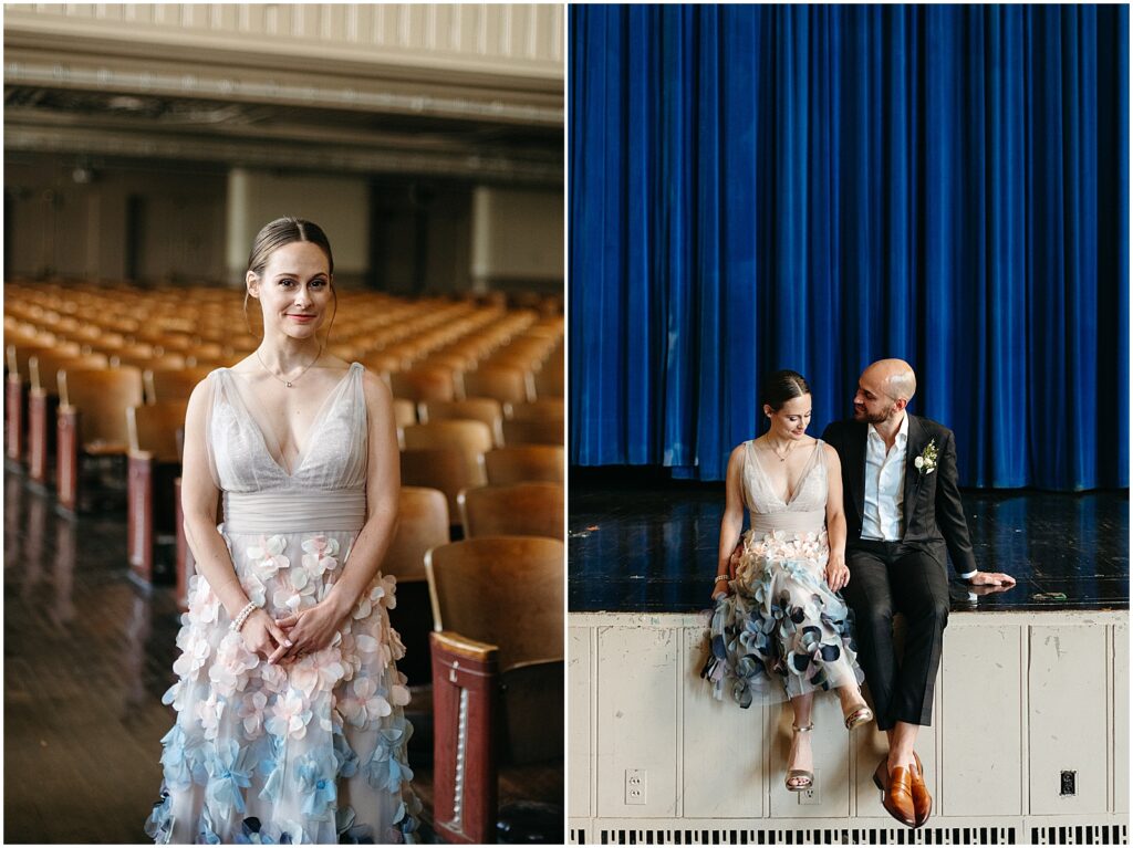 A bride and groom sit on an old school stage in front of a blue curtain.
