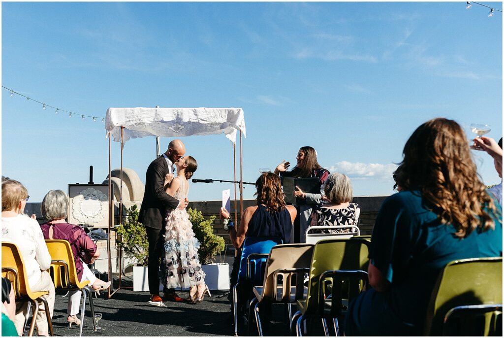 A bride and groom kiss at the end of a BOK Building wedding ceremony on the rooftop.