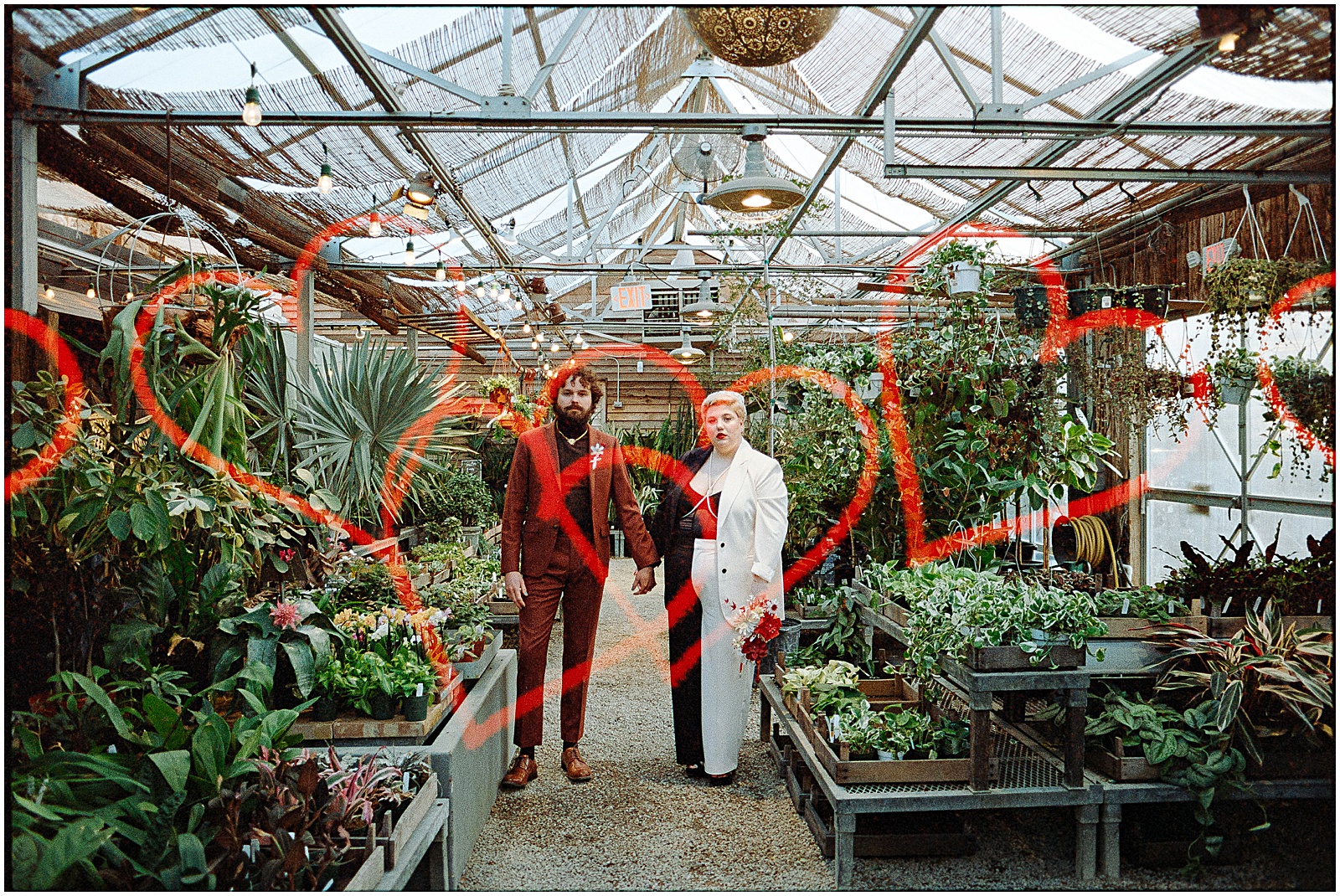 A couple poses in a Terrain greenhouse for modern wedding photography.