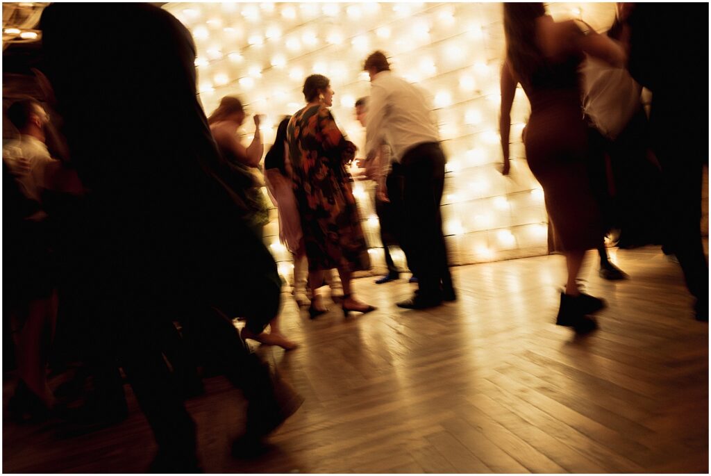 Guests dance beside a wall of lights.