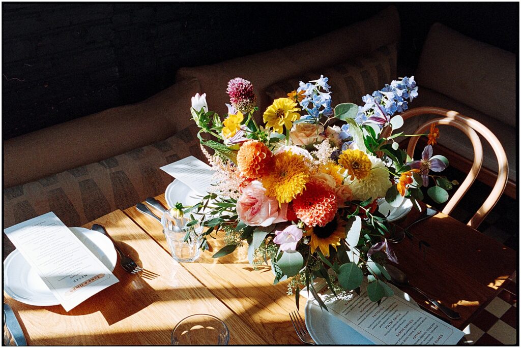 A colorful bridal bouquet sits beside a place setting at a restaurant wedding venue in Philadelphia.