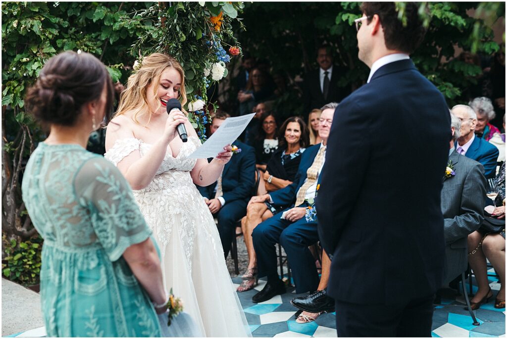 A bride reads her vows from a piece of paper at an outdoor wedding ceremony in Philadelphia.