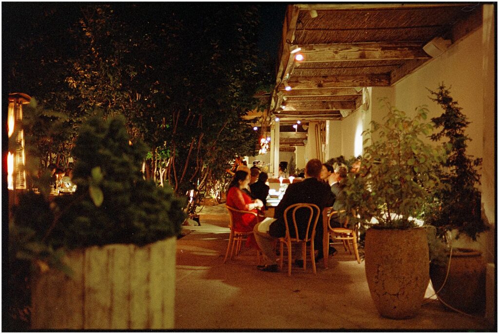 Guests sit in a courtyard under strings of lights.