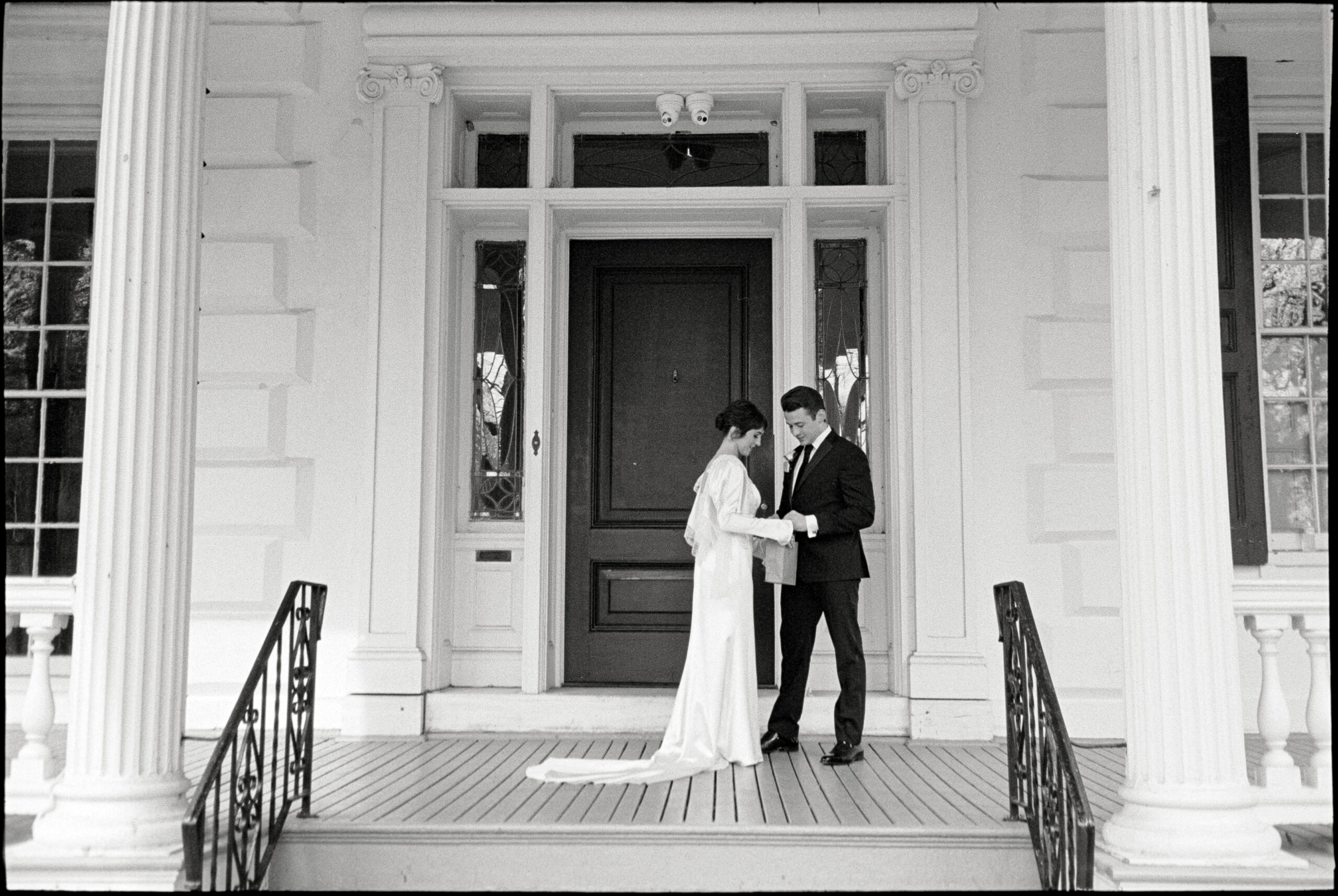 A bride and groom pose for Philadelphia wedding videography on the porch of a historic wedding venue.