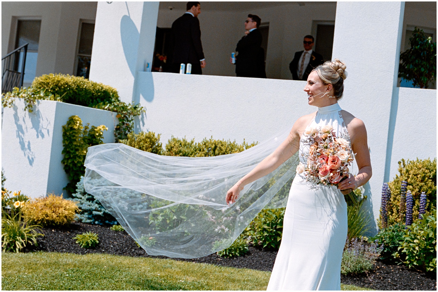 A Philadelphia bride poses on a lawn with her veil blowing in the wind.