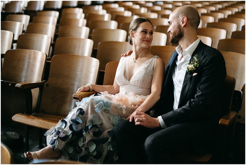 A bride and groom sit in vintage auditorium chairs before their minimalist wedding at the BOK Building.