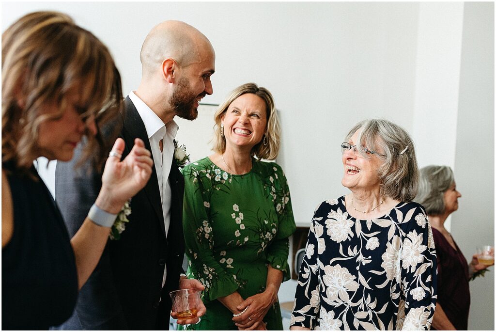 A groom laughs with his mother and aunt after a ketubah signing.