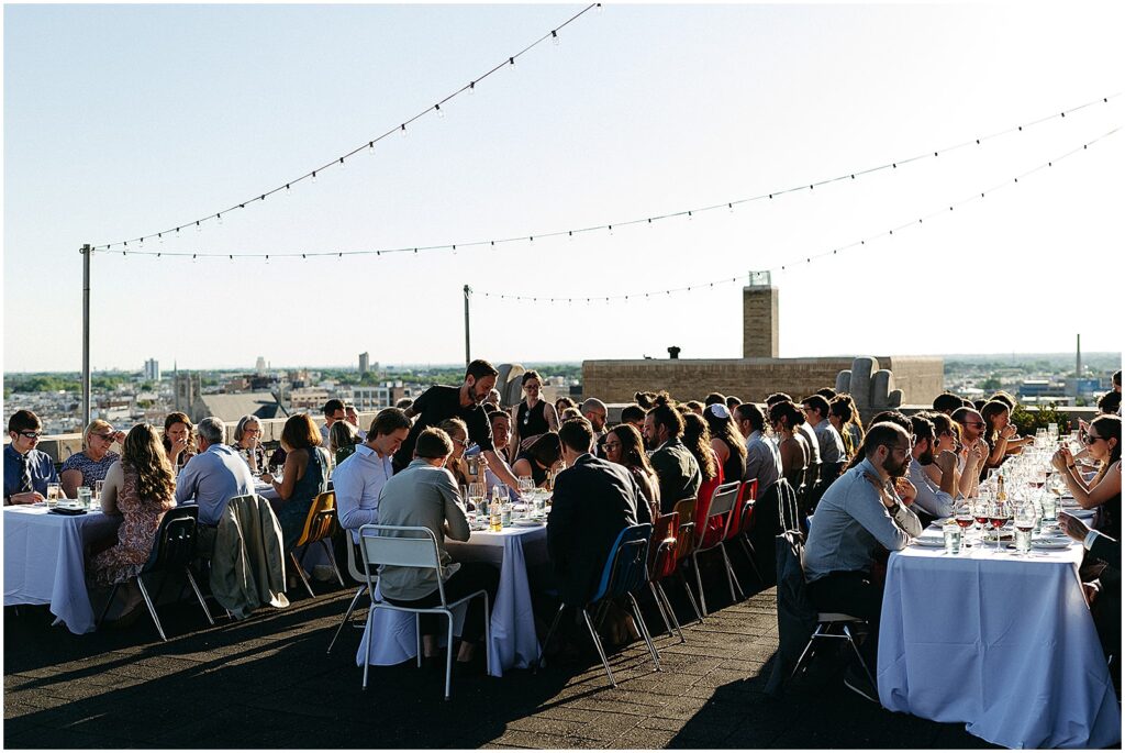 Servers walk between reception tables taking orders at a rooftop wedding at Irwin's.