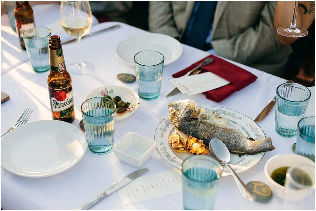 A plate of fish sits in the middle of a table with minimalist wedding decor.