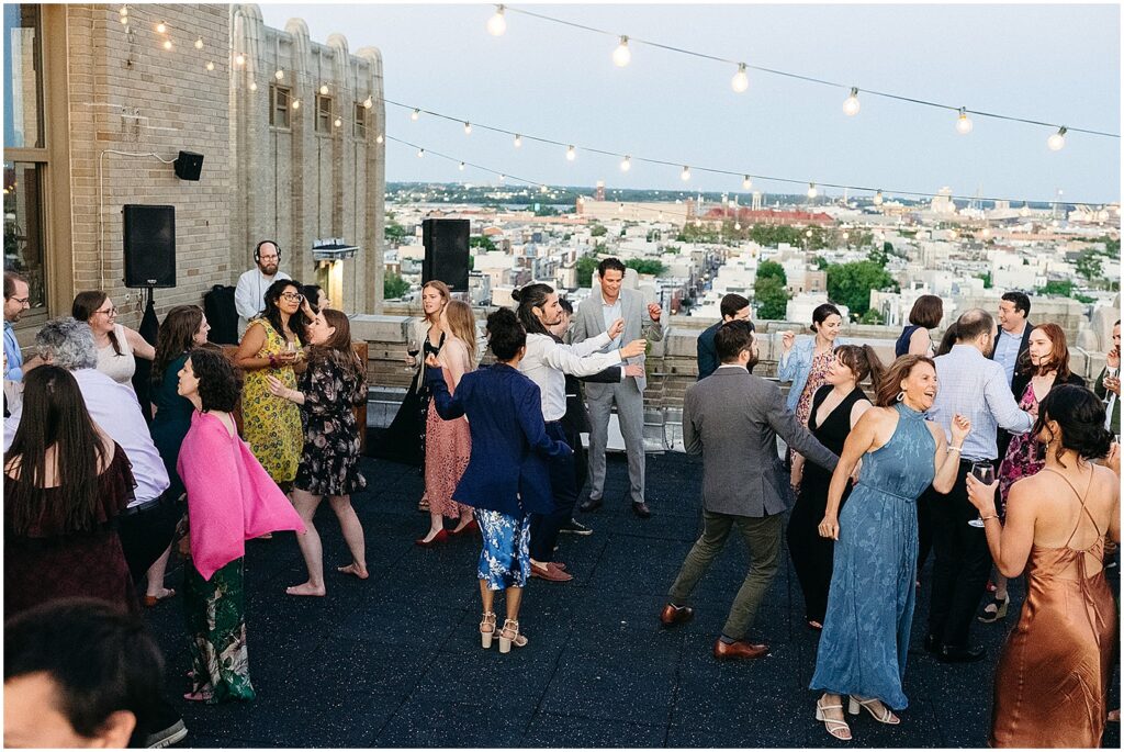 Wedding guests dance at a rooftop wedding venue overlooking Philadelphia.