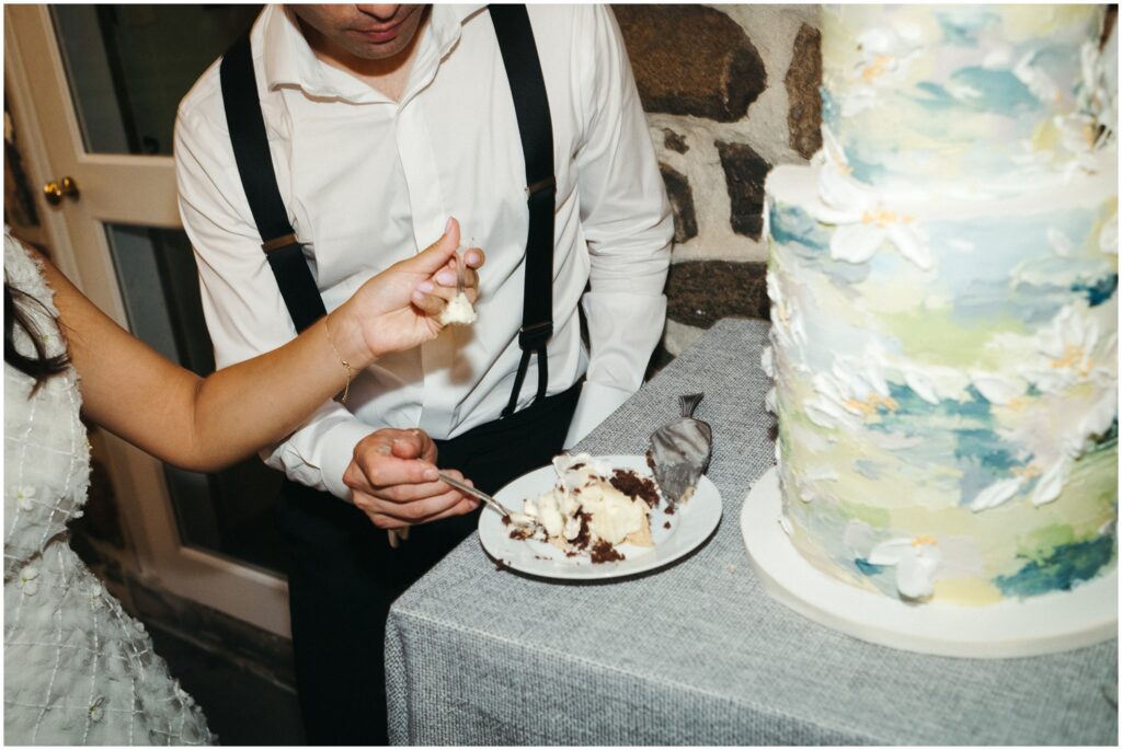 A bride and groom pick up bites of chocolate wedding cake.